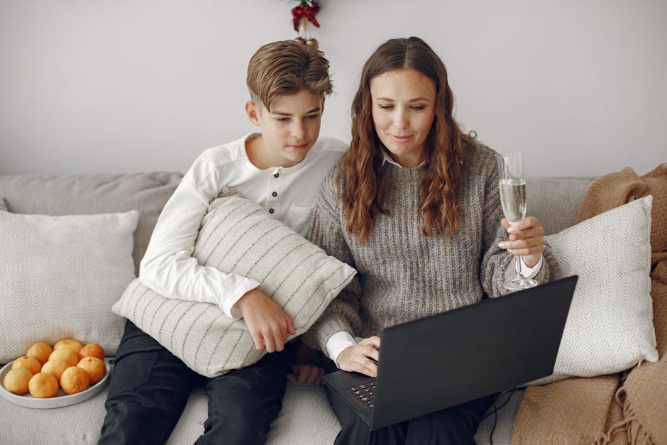 A mother and her teenage son sitting on a couch, shopping online using a laptop.