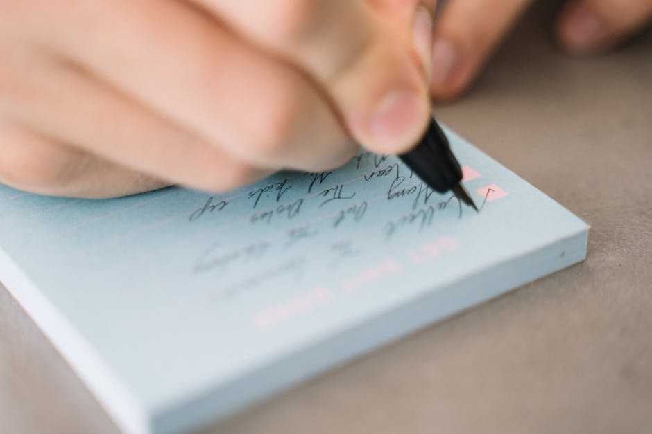 A close-up view of hand writing on a notepad, focusing on handwriting details.