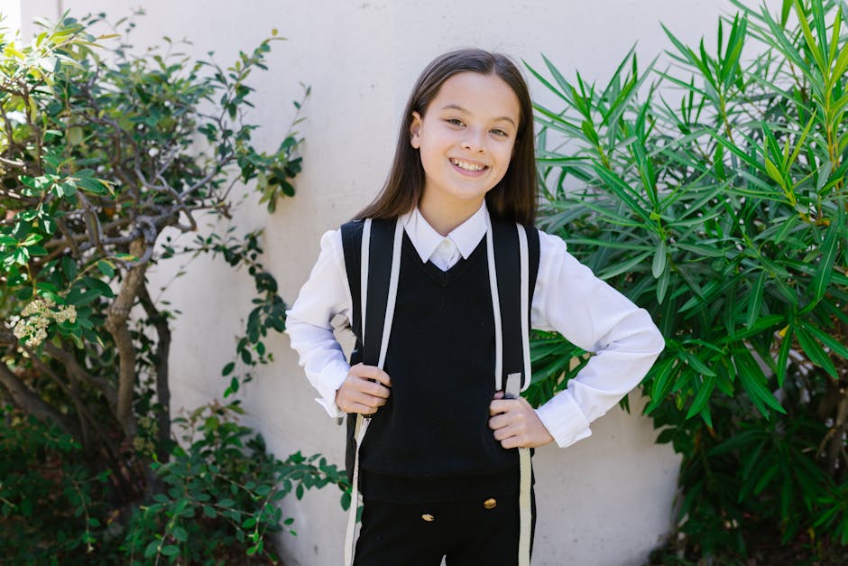 Confident young girl in school uniform smiling with backpack, ready for her first NAPLAN test